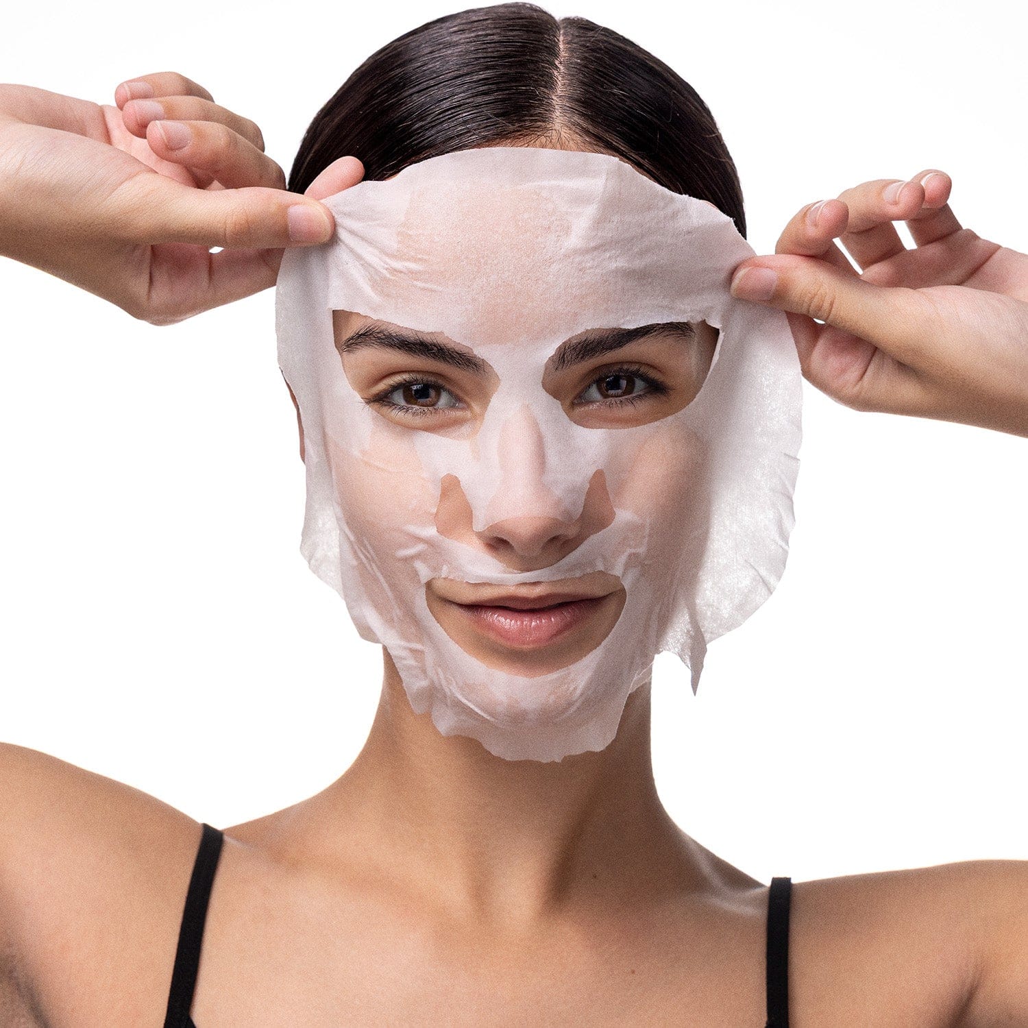 Woman applying Pestle & Mortar Pure Hyaluronic Acid Sheet Mask on a plain background